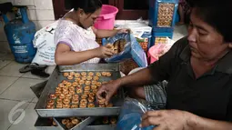 Pekerja menata kue kering kedalam kaleng di Industri kue rumahan Kwitang Pusaka, Jakarta,  (21/6). Jelang lebaran permintaan kue kering industri rumahan meningkat. (Liputan6.com/Faizal Fanani)