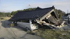 Sebuah kendaraan berada di bawah sebuah bangunan yang runtuh akibat gempa bumi di Shikamachi, prefektur Ishikawa, Jepang, Selasa (2/1/2024). (Kyodo News via AP)