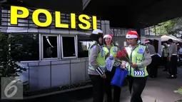 Petugas Kepolisian bersama sinterklas bersiap membagikan bunga dan masker di jalan kawasan Tomang, Jakarta, Rabu (23/12). Menyambut Hari Natal 2015, anggota Kepolisian Polres Jakarta Barat kenakan topi Sinterklas. (Liputan6.com/Yoppy Renato)
