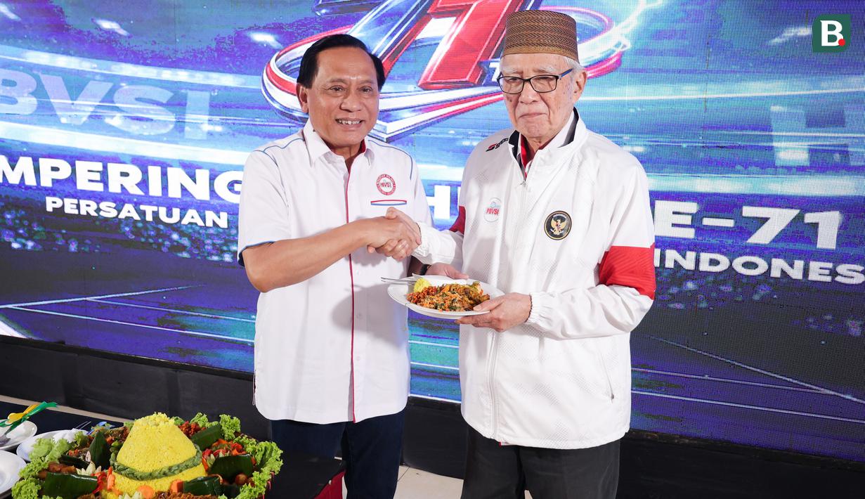 Ketua Umum Persatuan Bola Voli Seluruh Indonesia (PBVSI), Imam Sudjarwo (kiri) memberikan potongan tumpeng pertama kepada Purnama S. Yamil pada perayaan hari ulang tahun ke-71 yang dilaksanakan di Gedung Serbaguna Padepokan Voli Sentul, Kamis (26/2/2026) sore WIB. (Bola.com/Abdul Aziz)