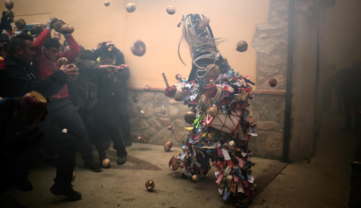 Orang-orang melempari pria berkostum ala setan dengan sayuran lobak selama Festival Jarramplas di kota Piornal, Spanyol, Sabtu (19/1). Di era modern sekarang makna tradisi ini menjadi simbolisasi pengusiran terhadap sesuatu yang buruk. (AP/Javier Fergo)