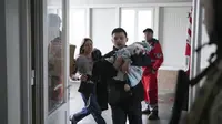 Marina Yatsko tampak berlari ketika putranya yang masih bayi digendong ke rumah sakit oleh kekasihnya pada Maret 2022. Bayi itu adalah korban serangan Rusia di Mariupol, Ukraina.&nbsp;(AP Photo/Evgeniy Maloletka, File)