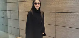 Sivia mengenakan pashimina hitam panjang polos serasi dengan abaya hitam polosnya. Dipadukan kacamata hitam sambi membawa tas hitamnya. Mengenakan sepatu sneakers hijau. [@siviazizah]