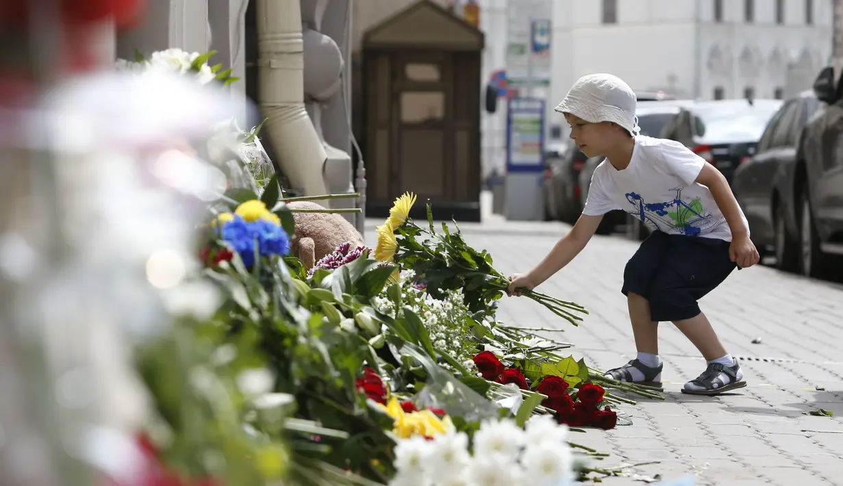 Anak kecil meletakkan buket bunga ucapan dukacita untuk para korban jatuhnya pesawat Malaysia Airlines MH17 di depan Kedutaan Besar Belanda di Moskow, Jumat (18/7/14). (REUTERS/Sergei Karpukhin)