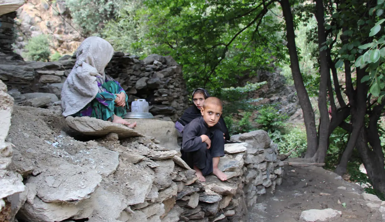Anak-anak duduk di atas bebatuan setelah banjir bandang menghantam wilayah Ursoon, daerah terpencil Chitral di Pakistan utara, Minggu (3/7). Banjir bandang akibat hujan lebat yang lama itu telah menewaskan sedikitnya 43 orang. (GUL HAMAAD Farooqi/AFP)