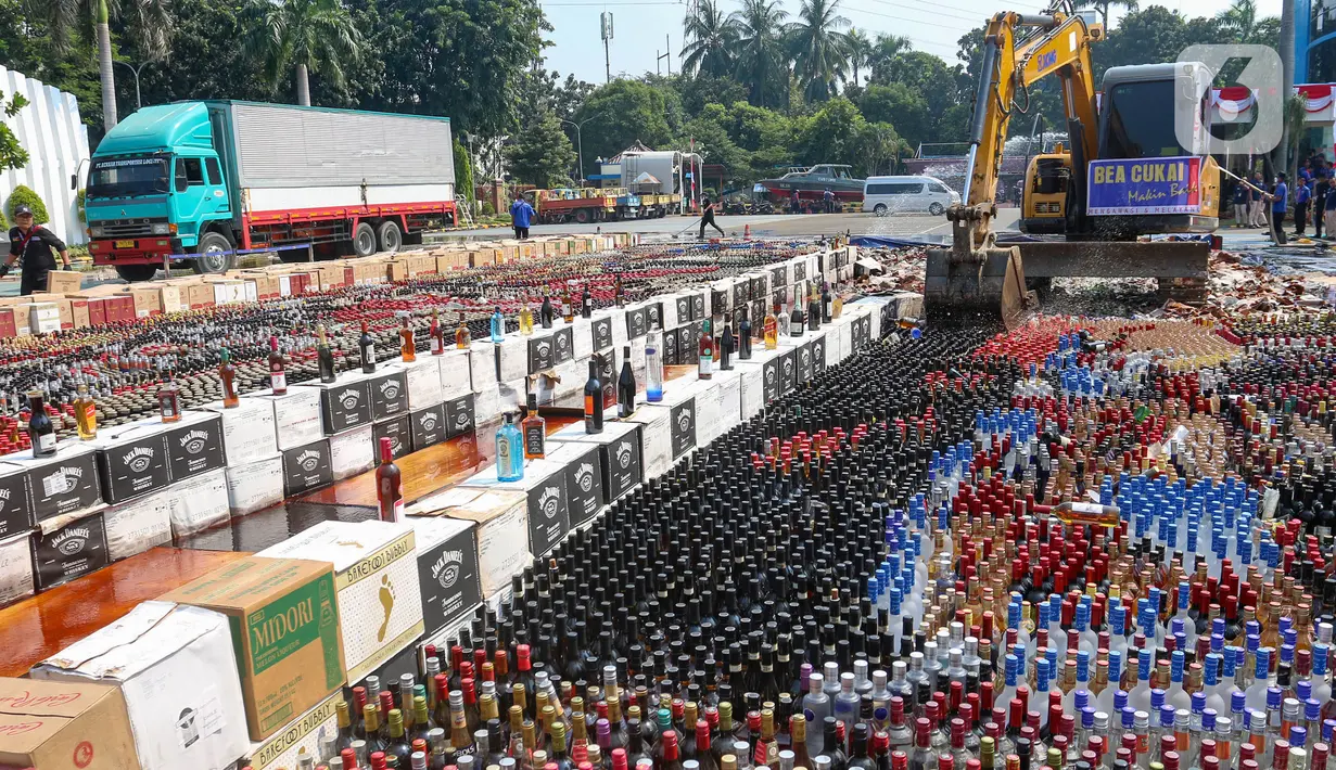 Petugas menggunakan alat berat eskavator saat memusnahkan minuman keras ilegal hasil penindakan di Kantor Pusat Bea Cukai, Jakarta Timur, Rabu (31/7/2024). (merdeka.com/Arie Basuki)