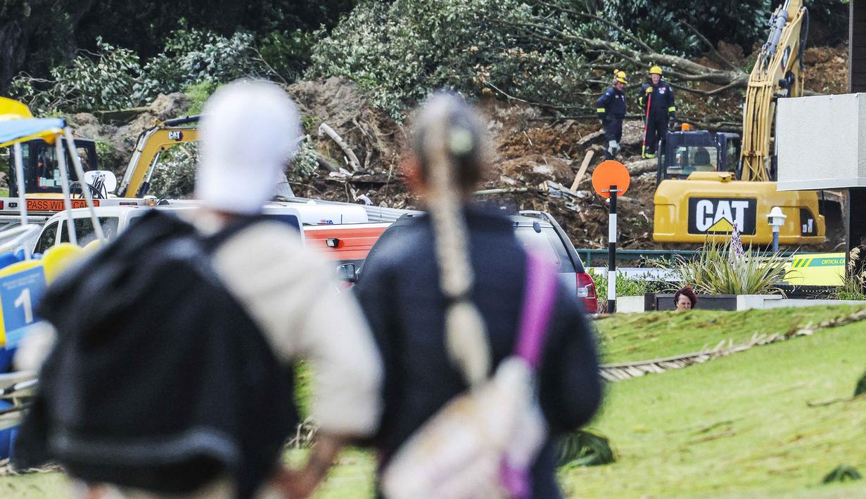 Operasi pencarian dan penyelamatan masih berlangsung di lokasi perkemahan Gunung Maunganui yang merupakan salah satu destinasi populer di pantai utara Selandia Baru. Tampak dalam foto, sepasang suami istri melihat tanah longsor sementara pencarian sedang dilakukan oleh layanan darurat setempat untuk orang hilang di Gunung Maunganui, Tauranga, Selandia Baru pada Kamis 22 Januari 2026. (DJ MILLS/AFP)