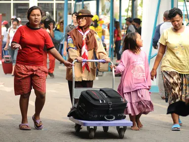 Seorang anggota Pramuka mendorong barang bawaan pemudik di kawasan Pelabuhan Merak, Banten, Kamis (22/6). Di Pelabuhan Merak, sejumlah anggota Pramuka diterjunkan untuk membantu pemudik membawa barang bawaan. (Liputan6.com/Helmi Fithriansyah)