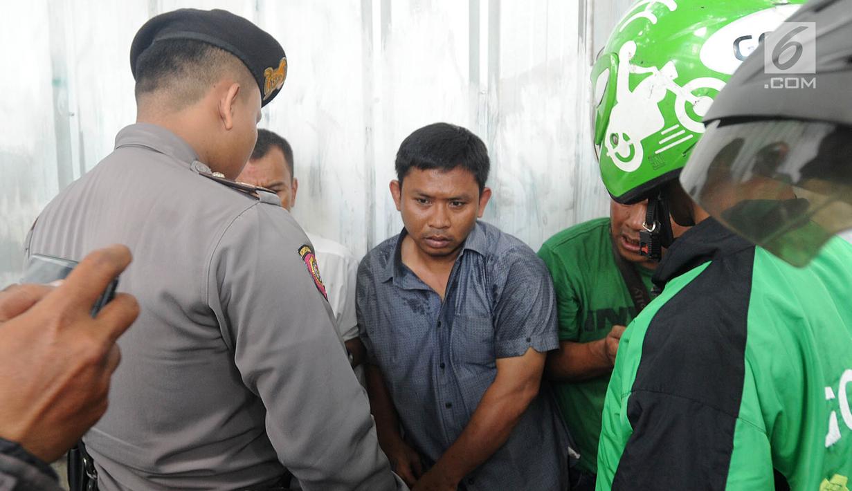 Polisi dan sejumlah pengemudi ojek online menginterogasi terduga copet sebelum dibawa menuju Mapolda Metro Jaya di Jalan Jenderal Sudirman, Jakarta (2/4). (Merdeka.com/Arie Basuki)