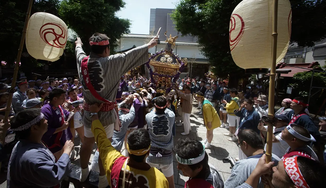 Peserta mengenakan pakaian tradisional Happi saat mengayunkan Mikoshi atau tempat suci portabel selama festival Tenno-sai di Kuil Susanoo di Tokyo, Jepang (3/6). Festival Tenno-sai ini digelar setiap tahunnya di Jepang. (AP Photo / Eugene Hoshiko)