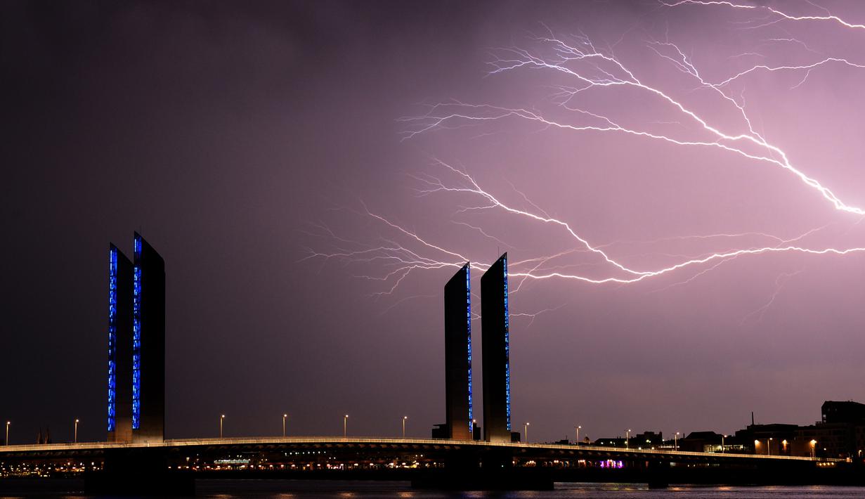 Kilatan petir yang terlihat diatas jembatan Bordeaux, Prancis (18/7). Kilatan ini hiasi langit Prancis saat terjadi badai petir. (AFP Photo/Nicolas Tucat)