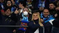 Seorang suporter Napoli mengenakan masker menunggu dimulainya pertandingan antara Napoli dan Barcelona di Stadion San Paolo di Naples, Italia, Selasa, (25/2/2020). Italia melaporkan kenaikan kasus infeksi virus Corona COVID- 91 menjadi lebih 272 kasus. (AFP Photo/Filippo Monteforte)