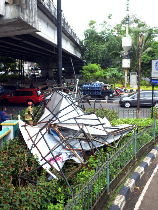 Kondisi papan reklame yang roboh saat sedang dipotong petugas pemadam kebakaran di Jalan Soepomo, Jakarta, Sabtu (28/5/2022). Hujan disertai angin kencang pada pagi tadi membuat papan reklame roboh sehingga membuat kemacetan arus lalu lintas di jalan tersebut. (merdeka.com/Imam Buhori)