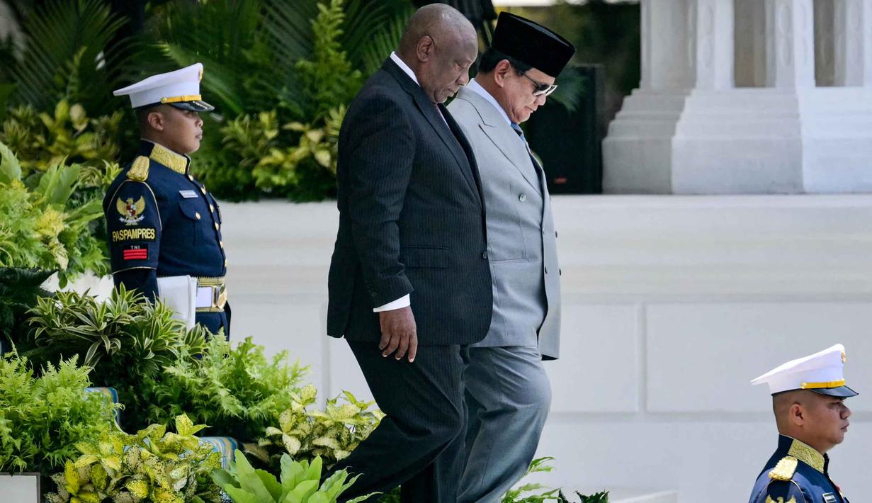 Presiden Republik Indonesia Prabowo Subianto (kanan) berjalan bersama Presiden Afrika Selatan Cyril Ramaphosa untuk memeriksa pasukan kehormatan di Istana Kepresidenan, Jakarta pada Rabu 22 Oktober 2025. (Bay ISMOYO/AFP)