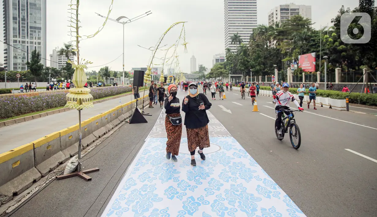 Sejumlah orang yang mengenakan batik berjalan di catwalk sepanjang Jalan Jenderal Sudirman, Jakarta, Minggu (2/10/2022). Kegiatan yang diikuti ratusan orang ini diselenggarakan oleh Bank Mandiri untuk menyambut Hari Batik Nasional yang jatuh setiap tanggal 2 Oktober 2022. (Liputan6.com/Faizal Fanani)
