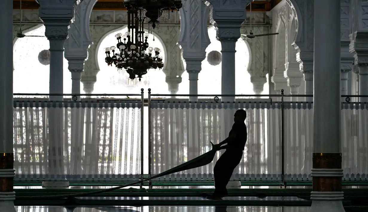 Beberapa pekerja terlihat sibuk menyiapkan serta membersihkan area yang akan digunakan umat Muslim untuk menjalankan salat tarawih. Tampak dalam foto, seorang pekerja menyiapkan karpet untuk salat tarawih pertama pada bulan suci Ramadan 1447 Hijriah di Masjid Agung Baiturrahman, Banda Aceh, Rabu 18 Februari 2026. (CHAIDEER MAHYUDDIN/AFP)