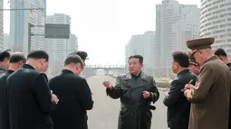 Pemimpin Korea Utara Kim Jong Un (tengah) berbincang dengan para pejabat saat memeriksa lokasi kompleks perumahan 10.000-flat yang sedang dibangun di Pyongyang (16/3/2022). Kim telah menghadiri upacara peletakan batu pertama situs tersebut Maret lalu. (AFP/STR/KCNA Via KNS)