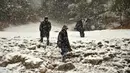 Wisatawan India berjalan di antara salju tebal yang menutupi Gulmarg, sekitar 55 km sebelah utara Srinagar, Kashmir, Selasa (3/1). Gelombang dingin yang melanda Kashmir kian parah hingga mencapai suhu di bawah nol derajat celcius. (Tauseef Mustafa/AFP)