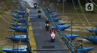 Pengendara sepeda motor melintasi jembatan perahu di atas Sungai Citarum, Karawang, Jawa Barat, Sabtu (20/11/2021). Jembatan perahu ini menjadi jalan alternatif yang menghubungkan antara Desa Anggadita dengan Kawasan Pabrik Dusun Rumambe 1. (merdeka.com/Imam Buhori)