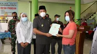 Wakil Bupati (Wabup) Sidoarjo Subandi menyerahkan sertifikat tanah kepada warga Desa Pabean Sedati. (Dian Kurniawan/Liputan6.com)
