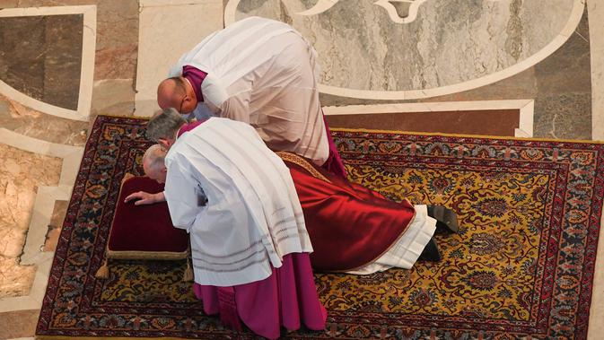 Paus Fransiskus mendapatkan bantuan ketika berdoa sambil berbaring dalam prosesi Jumat Agung memperingati penyiksaan Yesus sebelum disalibkan di Basilika Santo Petrus, Vatikan, Jumat (19/4). (Tiziana Fabi/Pool Photo via AP)
