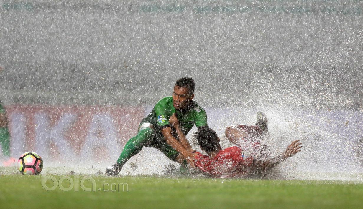 Pemian PS TNI, Ahmad Nufian Dani (kiri) berebut bola dengan pemain Persiba Balikpapan saat guyuran hujan pada laga pekan keempat Liga 1 2017 di Stadion Pakansari, Bogor, Jumat (5/5/2017). (Bola.com/Nicklas Hanoatubun)
