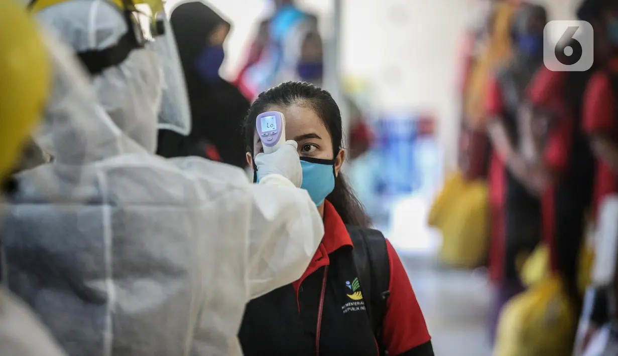 SeorangTKI Ilegal yang dipulangkan dari Malaysia diukur suhu tubuhnya setibanya di Pelabuhan Tanjung Priok, Jakarta, Jumat (12/6/2020). Sebanyak 436 TKI Ilegal tersebut nantinya akan dipulangkan ke daerah asalnya di 22 provinsi. (Liputan6.com/Faizal Fanani)