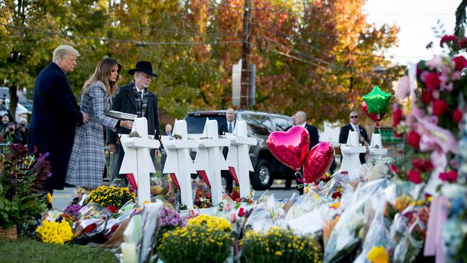Melania Trump didampingi Presiden Donald Trump dan Rabbi Jeffrey Myers meletakkan bunga di monumen peringatan penembakan maut di sinagog Tree of Life, Kota Pittsburgh, Pennsylvania, AS, Selasa (30/10). (AP Photo/Andrew Harnik)