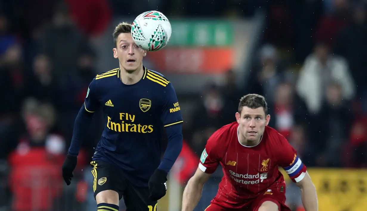 Gelandang Arsenal, Mesut Ozil berebut bola dengan gelandang Liverpool James Milner pada laga babak 16 Besar Carabao Cup di Anfield Stadium, Rabu (30/10/2019). Berimbang 5-5 di waktu normal, Liverpool menang 5-4 dalam adu penalti dan maju ke perempatfinal . (AP/Jon Super)