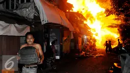 Warga menyelamatkan diri dari kebakaran yang terjadi di belakang Senayan City, Jakarta, Minggu (3/7) dini hari. Api diduga berasal dari korsleting listrik di salah satu rumah yang saat itu dalam keadaan kosong. (Liputan6.com/Helmi Afandi)