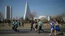 Peserta berlari melewati hotel Ryugyong selama Pyongyang Marathon atau yang disebut juga Mangyongdae Prize International Marathon di Pyongyang, Minggu (7/4). Ajang lari tahunan ini bagian dari perayaan untuk menandai hari lahir pendiri Korea Utara, Kim Il-sung pada tahun 1912. (KIM Won Jin / AFP)