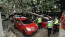 Petugas dibantu warga mengevakuasi pohon tumbang yang menimpa dua mobil yang terparkir di sebelah Pos Polisi Bundaran HI, Jakarta, Selasa (15/12). Tak ada korban jiwa akibat tumbangnya pohon yang disebabkan angin kencang itu. (Liputan6.com/Faizal Fanani)