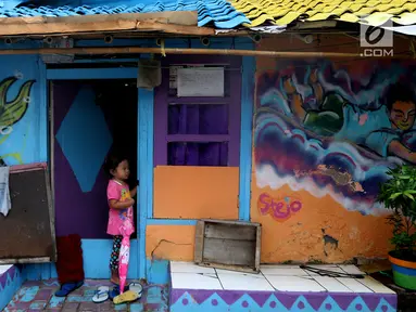 Seorang anak berdiri di depan pintu rumah dengan warna-warni cat dinding dan grafiti di Kampung Bekelir, Babakan Kota Tangerang, Jumat (16/11). Kampung ini dihuni sekitar 300 KK. (Liputan6.com/Fery Pradolo)