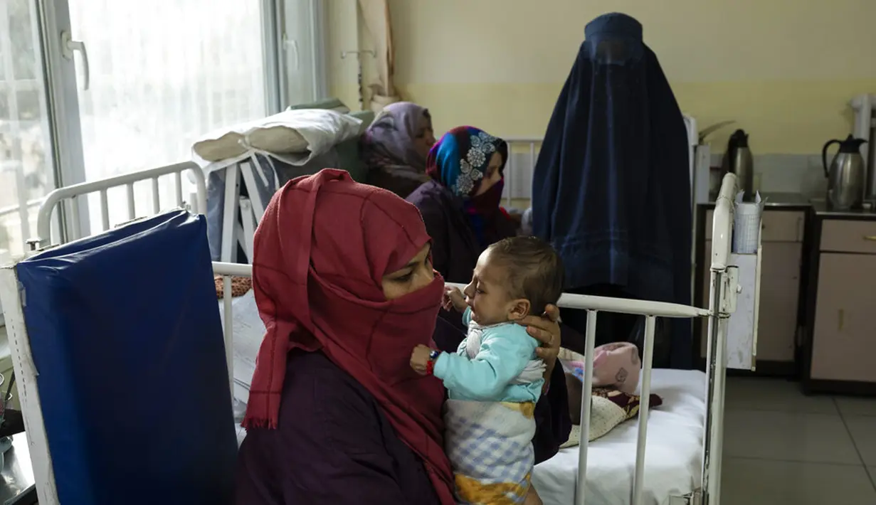 Lina menggendong bayinya, Osman, saat menjalani perawatan di bangsal gizi buruk RS Anak Nasional Ataturk, Kabul, Afghanistan, 2 Desember 2021. Menurut PBB dari awal November, hampir 24 juta orang di Afghanistan, sekitar 60 persen populasi, menderita kelaparan akut. (AP Photo/Petros Giannakouris)
