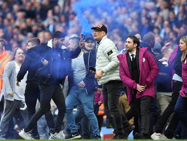 Fans menyalakan smoke bomb saat turun ke lapangan usai laga Manchester City melawan Swansea City pada lanjutan Premier League di Etihad Stadium, Manchester, (22/4/2018). Manchester City menang 5-0. (AFP/Paul Ellis)
