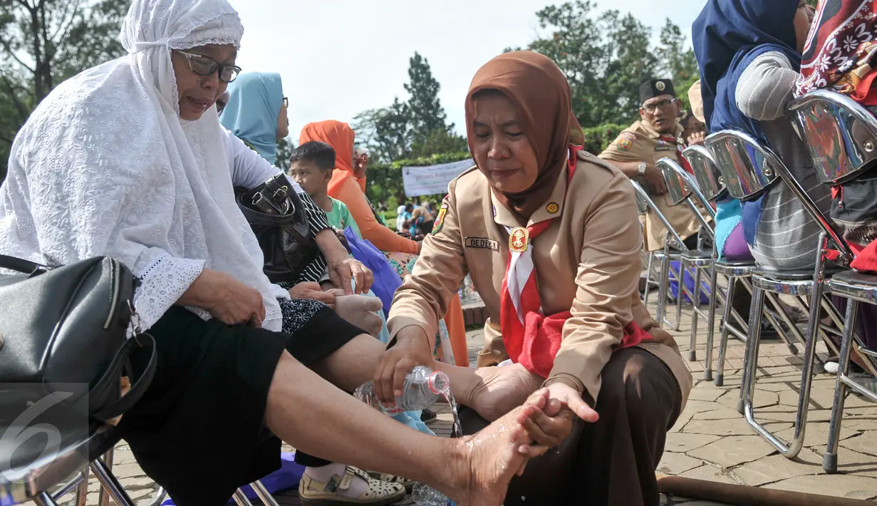 Pembina anggota Kwarnas Gerakan Pramuka menangis sambil membasuh kaki ibunya di Taman Wiladatika Cibubur, Jakarta, Rabu (21/12). Aksi massal membasuh kaki ibu itu dalam rangka memperingati Hari Ibu 2016. (Liputan6.com/Yoppy Renato)