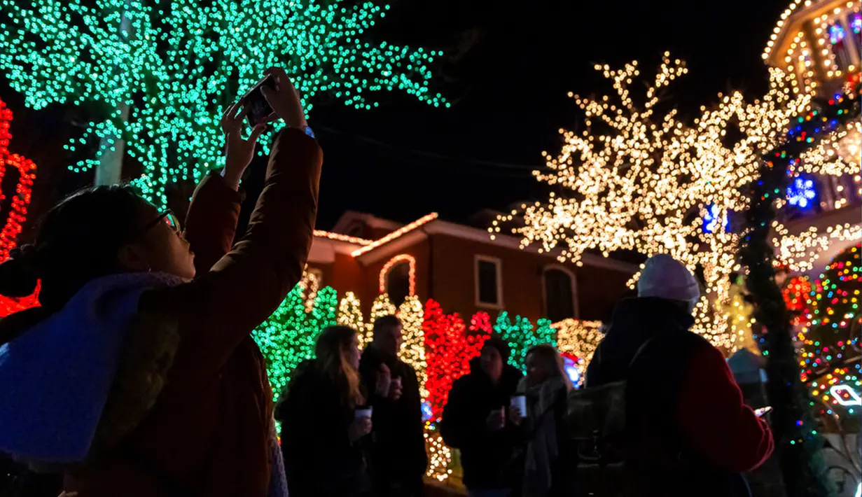 Seorang wisatawan memotret sebuah rumah yang dihiasi lampu Natal di lingkungan Dyker Heights, Brooklyn, New York, Amerika Serikat, 21 Desember 2022. Dyker Heights adalah salah satu kawasan Kota New York yang paling menakjubkan dengan dekorasi meriah selama musim libur akhir tahun. (AP Photo/Julia Nikhinson)