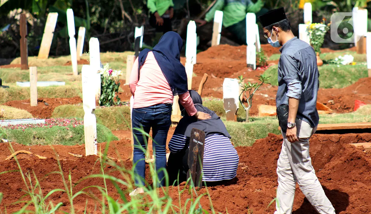 Peziarah berdoa di sisi makam jenazah yang diduga terinfeksi virus COVID-19 di TPU Pondok Ranggon, Jakarta, Minggu (24/5/2020). Momen Hari Raya Idul Fitri 1441 H dimanfaatkan sejumlah keluarga dan kerabat korban yang diduga terinfeksi COVID-19 untuk berziarah. (Liputan6.com/Helmi Fithriansyah)