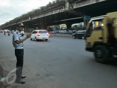 Petugas Dishub mengatur kendaraan yang melintasi Jalan TB Simatupang, Jakarta, Senin (12/12). Dinhubtrans Jaksel menyiagakan petugas di sejumlah titik rawan kemacetan untuk antisipasi penumpukan kendaraan saat arus balik. (Liputan6.com/Yoppy renato)