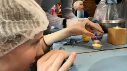 Wanita dan anak-anak Ukraina menghias telur Paskah untuk tentara dalam restoran Georgia di Lviv, Ukraina, 20 April 2022. Lebih dari selusin wanita dan anak-anak menghias telur rebus dan es roti Paskah tradisional dengan warna kuning dan biru, warna bendera Ukraina. (Alice HACKMAN/AFP)