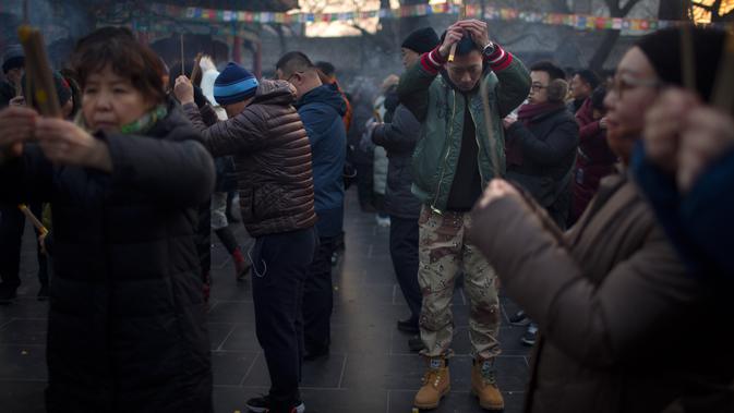 Orang-orang memegang dupa saat berdoa di Kuil Lama di Beijing (5/2). Orang-orang China merayakan hari pertama Tahun Baru Imlek pada hari Selasa, Tahun Babi di zodiak Tiongkok dengan berdoa di kuil. (AP Photo/Mark Schiefelbein)