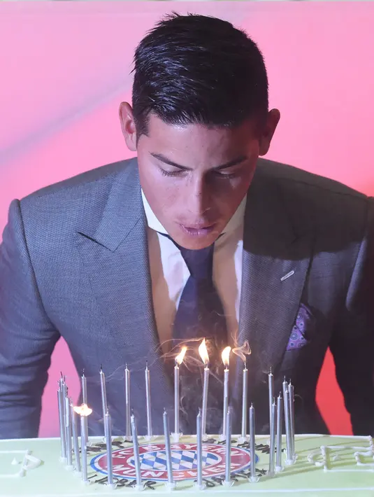 Gelandang baru Bayern Munchen, James Rodriguez meniup lilin di kue ulang tahunnya saat konferensi pers kepindahannya ke Bayern Munchen Jerman, (12/7).  (Felix Hoerhager / dpa via AP)