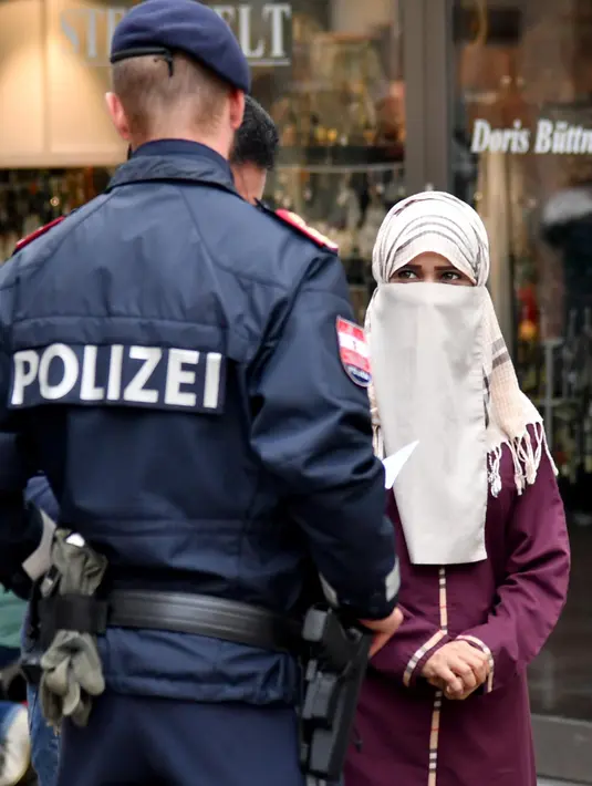 Wanita muslim menatap petugas kepolisian yang merazia penggunaan cadar di tempat umum di kota Zell am See, Minggu (1/10). Pemerintah Austria mengeluarkan undang-undang baru yang melarang seseorang menggunakan penutup wajah. (BARBARA GINDL/APA/AFP)