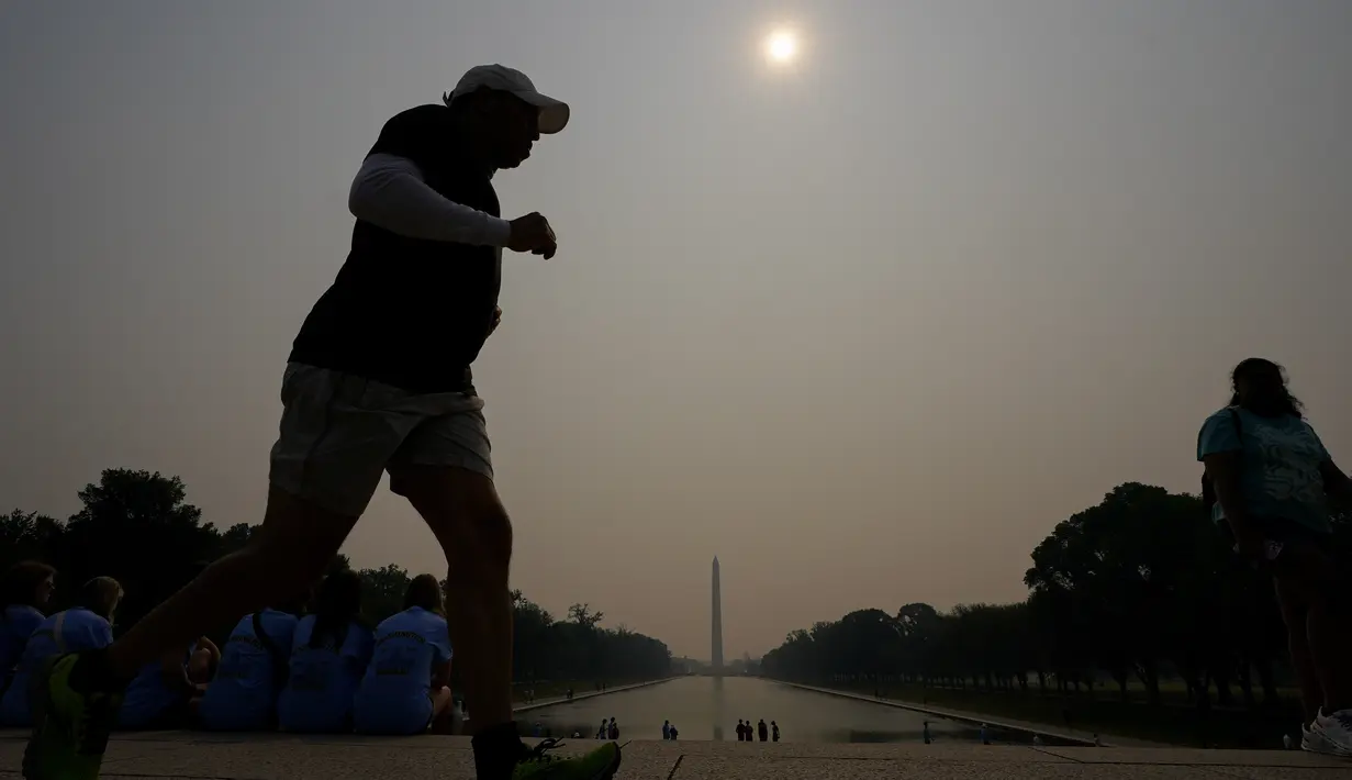 Sementara Monumen Washington dan National Mall diselimuti kabut kelabu tanpa hujan, di mana pada satu titik ada seorang pelari yang berlari. (AP Photo/Julio Cortez)