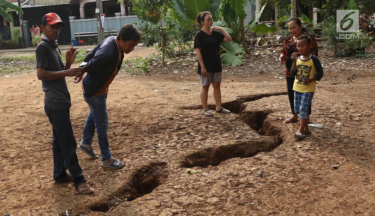 Warga mengamati tanah terbelah di lapangan RT 02 RW 02 Kampung Pedurenan, Kelurahan Cisalak Pasar, Cimanggis, Depok, Jawa Barat, Senin (22/10). Tanah terbelah tersebut kini dalam penyelidikan. (Liputan6.com/Immanuel Antonius)