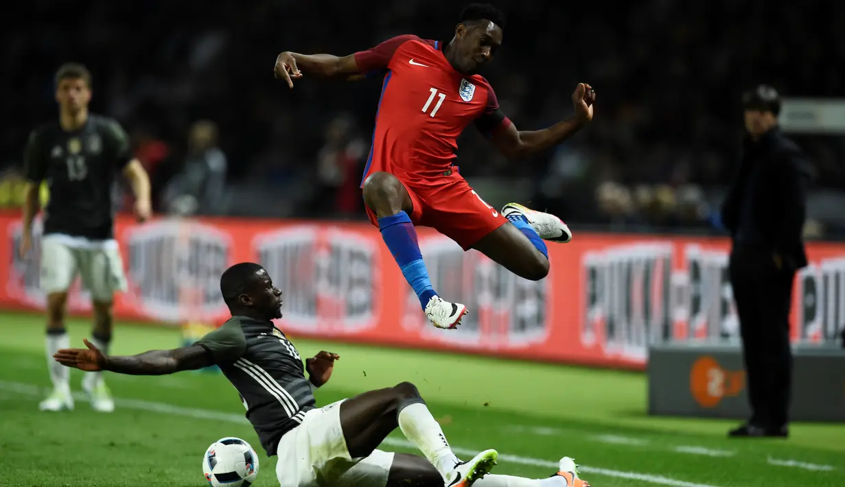 Striker Inggris, Danny Welbeck, melompat menghindari sapuan kaki pemain Jerman, Antonio Ruediger, dalam laga persahabatan di Olympiastadion, Berlin, Jerman, (26/3/2016). (AFP/Odd Andersen)