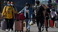 Wisatawan mengenakan masker wajah dengan barang bawaan mereka meninggalkan stasiun kereta api Beijing di Beijing, Selasa (6/9/2022). China lockdown jutaan warganya di bawah pembatasan ketat COVID-19. (AP Photo/Andy Wong)