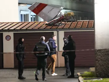 Petugas polisi berdiri di dekat ekor pesawat kecil yang melakukan pendaratan darurat di sebuah kediaman, di Villejuif, luar Paris, Senin (4/12/2023). (AP Photo/Michel Euler)