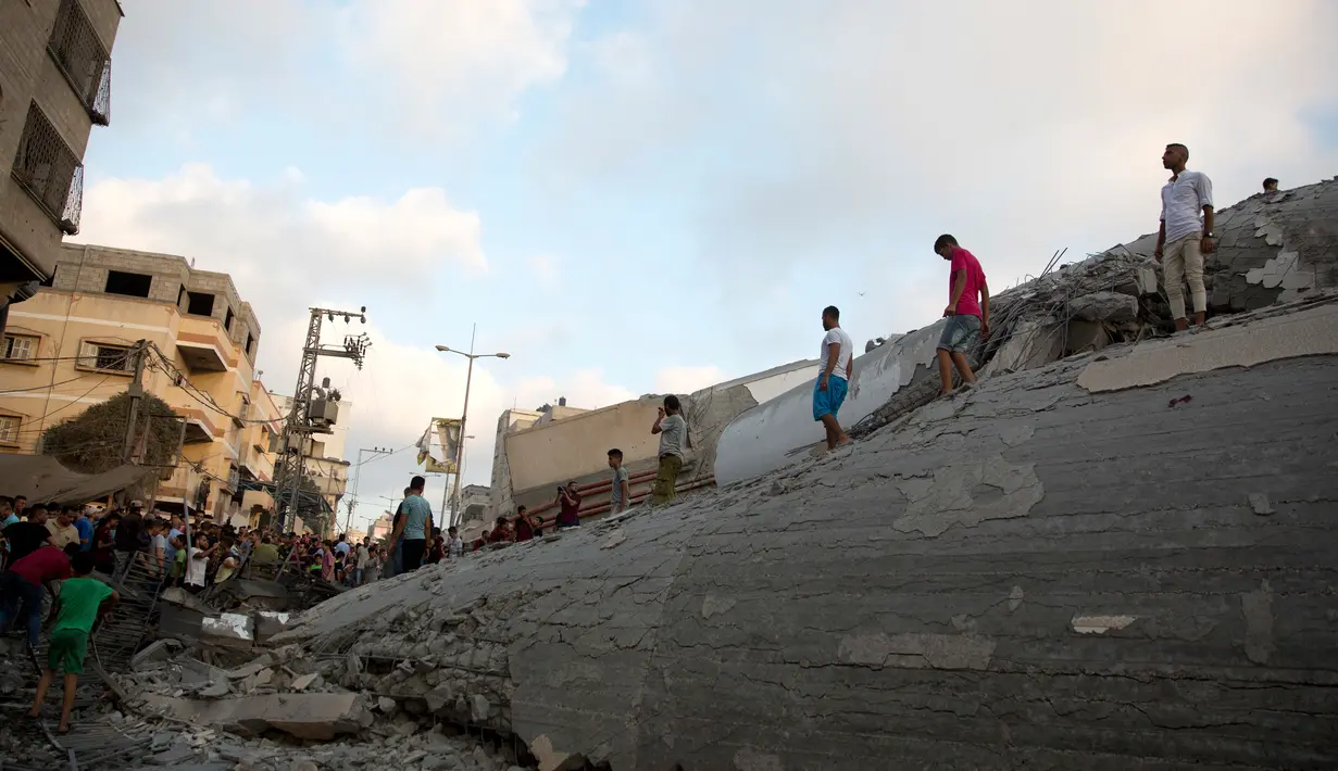 Warga melihat puing-puing bangunan yang hancur akibat serangan udara Israel di Kota Gaza, Palestina, (9/8). Israel mengerahkan lebih dari 140 serangan udara yang menargetkan posisi militan Hamas di Gaza. (AP Photo/Khalil Hamra)