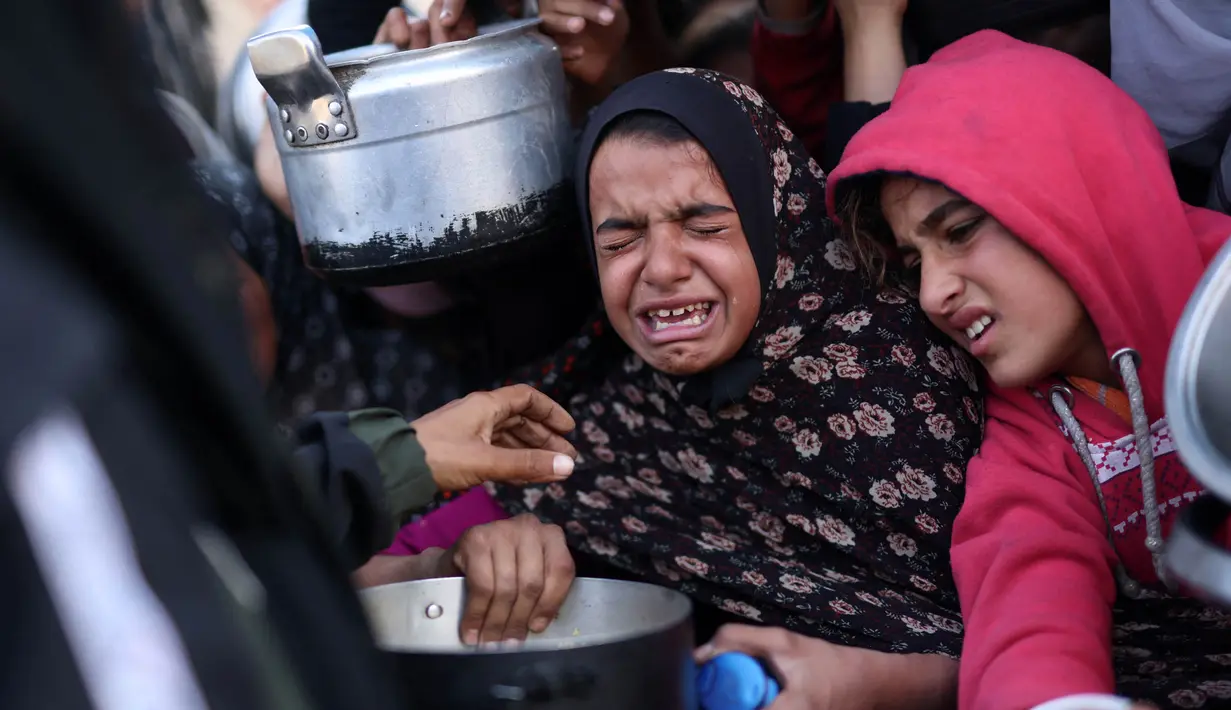 Krisis pangan yang berujung pada bencana kelaparan membuat anak-anak pengungsi Palestina di wilayah Khan Yunis, selatan Gaza harus ikut berjuang antre untuk mendapatkan makanan. (BASHAR TALEB/AFP)